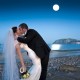 Bride and groom kiss under full moon